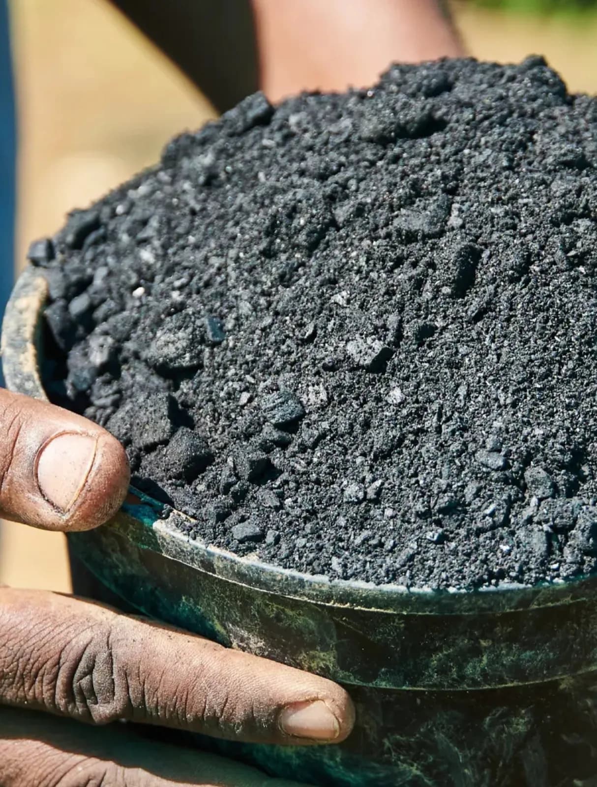 Hands holding a container filled with granular biochar